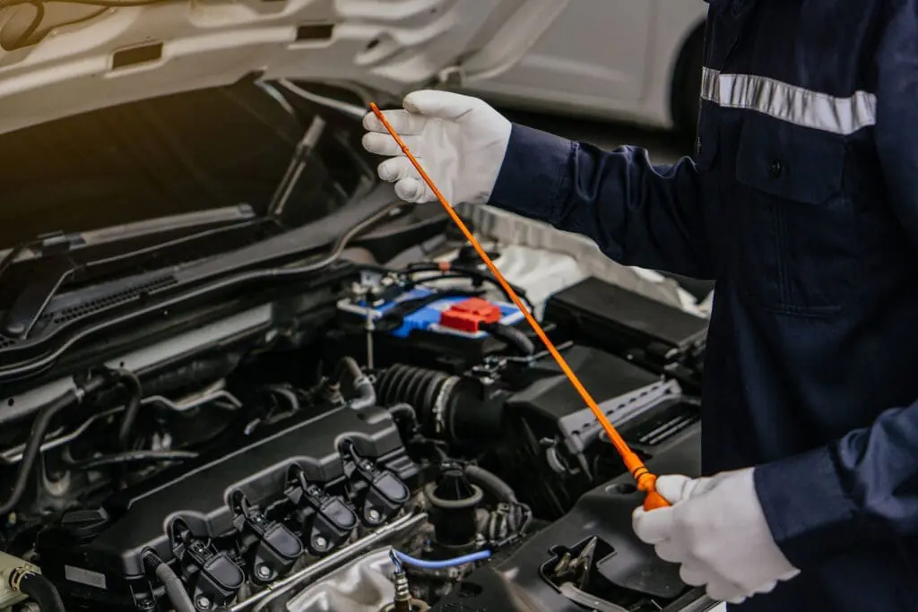 Mechanic man checking car engine oil of the car in